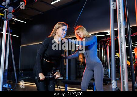 Un personal trainer controlla una donna atletica durante il suo allenamento. Concentratevi su come ottenere il giusto esercizio in palestra Foto Stock