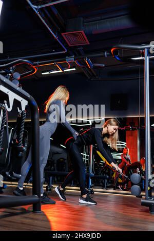 Un personal trainer controlla una donna atletica durante il suo allenamento. Concentratevi su come ottenere il giusto esercizio in palestra Foto Stock