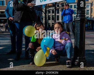 Due bambini ucraini sono visti seduti a terra mentre ascoltano gli interventi durante la manifestazione. Il popolo ucraino si è riunito di fronte all'Ufficio dei rappresentanti della Commissione europea, all'Aia, per continuare a protestare contro l'invasione di Putin e per chiedere all'UE di accelerare la sua domanda di adesione perché i Paesi Bassi si sono opposti accelerano il processo, hanno chiesto a tutta la comunità di unirsi per influenzare la posizione ufficiale. A partire da oggi, i leader europei discuteranno della richiesta di Ukraineís quando si riuniranno in due giorni nei pressi di Parigi. Foto Stock