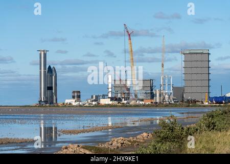 Due prototipi Starship e un razzo Super Heavy Booster cilindrico presso lo stabilimento di assemblaggio SpaceX di Boca Chica, Texas. Lo Starship è alto 160', Foto Stock