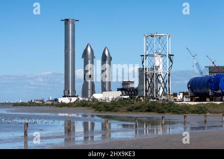 Due prototipi Starship e un razzo Super Heavy Booster cilindrico presso lo stabilimento di assemblaggio SpaceX di Boca Chica, Texas. Lo Starship è alto 160', Foto Stock