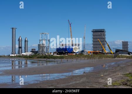 Due prototipi Starship e un razzo Super Heavy Booster cilindrico presso lo stabilimento di assemblaggio SpaceX di Boca Chica, Texas. Lo Starship è alto 160', Foto Stock