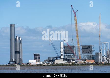 Due prototipi Starship e un razzo Super Heavy Booster cilindrico presso lo stabilimento di assemblaggio SpaceX di Boca Chica, Texas. Lo Starship è alto 160', Foto Stock