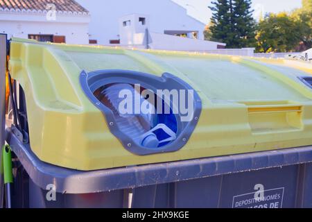 Contenitore giallo disposto in prossimità di un'area residenziale per la raccolta selettiva di contenitori in plastica Foto Stock