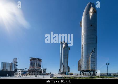 Due prototipi Starship e un razzo Super Heavy Booster cilindrico presso lo stabilimento di assemblaggio SpaceX di Boca Chica, Texas. Lo Starship è alto 160', Foto Stock