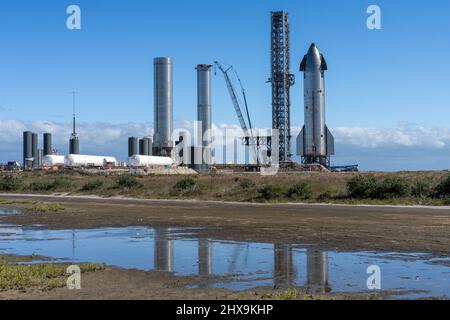 Uno Starship e due razzi cilindrici Super Heavy Booster della torre di lancio SpaceX a Boca Chica, Texas. Lo Starship è alto 160', mentre il Supe Foto Stock