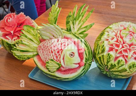 Cocomeri maturi splendidamente scolpiti a forma di fiore e pesce Foto Stock