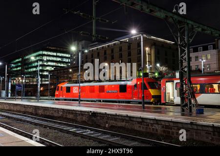 DB cargo rail classe 90 locomotiva elettrica 90028 presso la stazione ferroviaria di London Kings Cross a noleggio per LNER in una notte buia Foto Stock