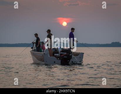 Pesca al trambuco sul lago Kabetogama, Parco Nazionale Voyageurs. Come il sole serale tramonta sullo sfondo. Foto Stock