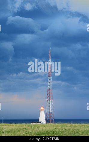Faro e torre di comunicazione con sfondo di nuvole tempesta, a Capo Nord, Seacow Pond, Prince Edward Island, Canada Foto Stock