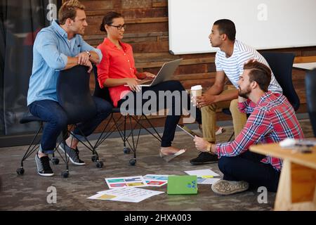 Theres un brainstorm creativo che continua dentro qui. Foto di un gruppo di giovani designer che hanno un incontro informale. Foto Stock