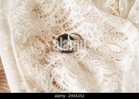 Essi simboleggiano il nostro impegno a vicenda per tutta la vita. Foto vita di due splendidi anelli di matrimonio in cima a un abito da sposa. Foto Stock