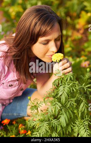 Odori come primavera. Scatto corto di una donna che odora un fiore giallo. Foto Stock