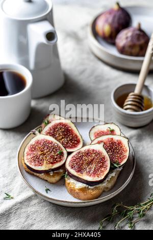 Due sandwich con fichi, timo su sfondo testurizzato. Composizione della colazione Foto Stock