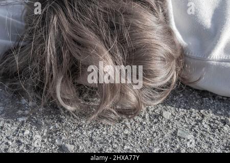 Omicidio sulla strada. Il corpo di una ragazza adolescente in un maglione bianco si trova sull'asfalto sulla strada. Vittima di un incidente stradale. Il concetto di kidn Foto Stock