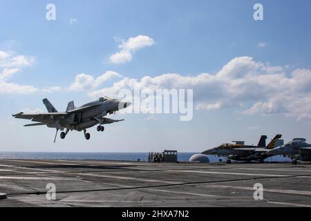 PHILIPPINE SEA (10 marzo 2022) un Super Hornet F/A-18E, assegnato ai 'Tophatters' di Strike Fighter Squadron (VFA) 14, si prepara a fare un atterraggio arrestato sul ponte di volo del vettore aereo di classe Nimitz USS Abraham Lincoln (CVN 72). Abraham Lincoln Strike Group è in fase di implementazione pianificata nell'area delle operazioni della flotta USA 7th per migliorare l'interoperabilità attraverso alleanze e partnership, fungendo da forza di risposta pronta a supportare una regione indopacifica libera e aperta. (STATI UNITI Foto Navy di Sint. Di comunicazione di massa Seaman Aprentice Julia Brockman) Foto Stock