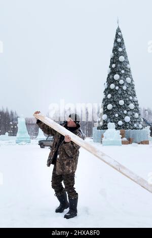 Costruttore con un bordo nelle sue mani sullo sfondo dell'albero di Natale Foto Stock