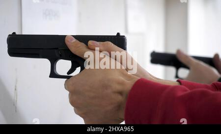 L'istruttore insegna a un uomo di maneggiare un'arma o una pistola. Primo piano delle mani maschili con pistola mentre si allenano con l'istruttore. Primo piano del ricaricamento manuale dell'uomo Foto Stock