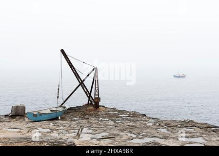 Vista di Portland Bill con la gru rossa e la barca blu sulla sinistra e la barca da pesca sul mare sullo sfondo Foto Stock