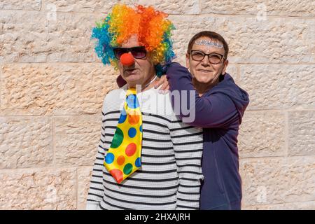 Divertente coppia senior vestita per Halloween o Purim o festa di compleanno. Divertente vecchio uomo in un costume clown e donna anziana felice con volto adesivi celebrazione Purim Ebraica Vacanza. Foto Stock