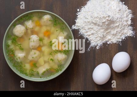 Vista superiore della zuppa nella ciotola con gnocchi sullo sfondo di legno Foto Stock
