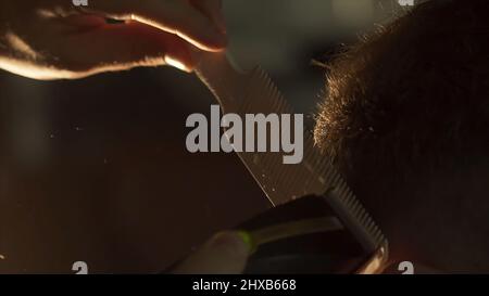 L'uomo ottiene un taglio freddo dei capelli nel barbiere. Telaio. Mani di capelli professionale stylist taglio capelli cliente scatto. Primo piano della mano dell'estetista con le forbici Foto Stock