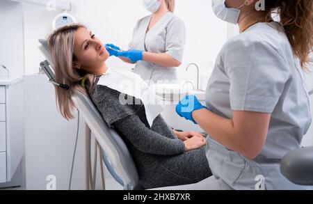 bella ragazza caucasica con denti si siede in una sedia dentale. Dentista professionista aiuta la sua paziente in Pain.doloroso trattamento aiuto. Copia spa Foto Stock