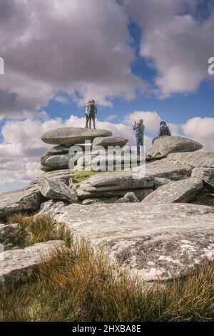 Camminatori che posano su una pila di roccia di granito formata dall'azione glaciale e che hanno la loro fotografia scattata su Stowes Hill su Bodmin Moor in Cornovaglia. Foto Stock