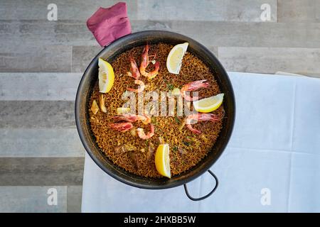 Paella di pesce tradizionale spagnola nella padella. Pronto da mangiare. Cucina libri concetto. Foto Stock