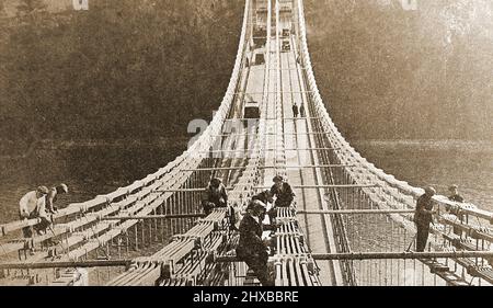 Un'immagine iniziale che mostra i lavoratori che dipingano il ponte sospeso Menai, Anglesey, Galles, Regno Unito senza alcun equipaggiamento di sicurezza. Foto Stock