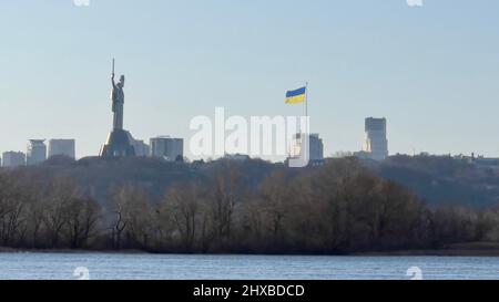 Il monumentale Monumento della Patria, alto 102 metri, fa parte del Museo della seconda Guerra Mondiale, e la bandiera Ucraina che vola a Kiev, Ucraina, durante l'i Russo Foto Stock