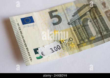 Banconota da cinque euro con prezzo di tre euro. Focalizzazione selettiva sull'etichetta. Inflazione in Europa, iperinflazione, concetto di svalutazione. Foto Stock