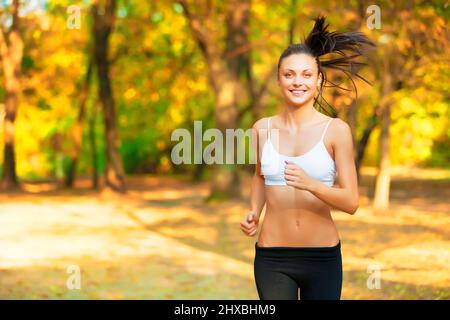 Tempo impressionante per una corsa. Scatto di una giovane donna dall'aspetto positivo che fa jogging in un parco in autunno. Foto Stock