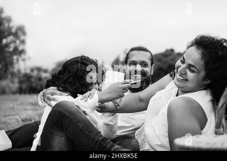 Felice famiglia indiana che si diverte a dipingere con i bambini al parco della città - Focus on madre faccia Foto Stock