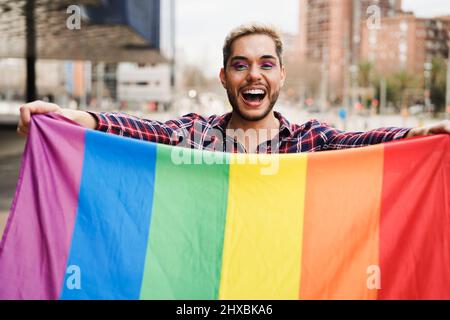 Gay uomo che ha divertimento tenendo la bandiera arcobaleno lgbt all'aperto - Pride Concept Foto Stock