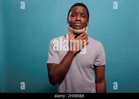 Adulto in dolore che indossa il collo cervicale per recuperare da un incidente di frattura, sensazione di turbamento per il dolore fisico. Uomo ferito con schiuma di rinforzo del collo che tratta il problema di trauma spinale e la sofferenza. Foto Stock