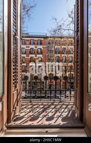 Vista della città attraverso un balcone di un vecchio edificio che si affaccia sulla strada con finestre e persiane di legno Foto Stock