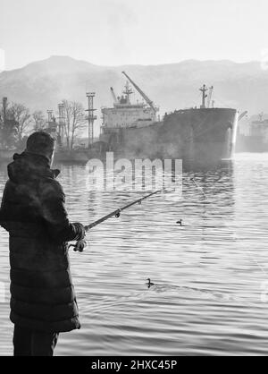 Pescatore sul terrapieno di mattina presto, quando la nebbia cadde Foto Stock