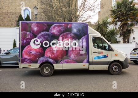 Primo piano vista laterale delle prugne su un pulmino di consegna Ocado e autista su una strada suburbana a Londra, Inghilterra, Regno Unito Foto Stock