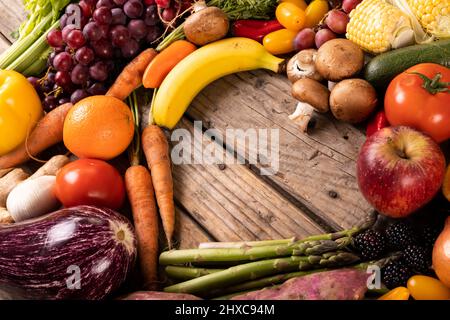 Vista ad angolo alto di varie verdure e frutta con forma a cuore vuota su tavola di legno Foto Stock