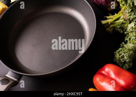 Primo piano della padella nera vuota di kale e peperone rosso sul tavolo Foto Stock