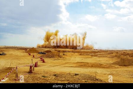 Detriti di roccia e nubi di polvere durante l'esplosione del detonatore nel cantiere Foto Stock