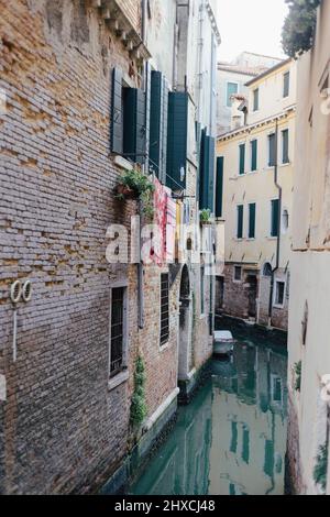 Canale molto stretto nella zona densamente edificata di Venezia Foto Stock