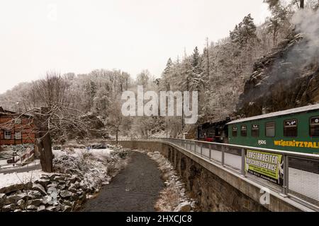 Rabenau, neve nella valle 'Rabenauer Grund', fiume 'Rote Weißeritz', treno a vapore a scartamento ridotto di Weißeritztalbahn (Weisseritz Valley Railway) alla stazione Rabenau, Erzgebirge / Ore Mountains, Sachsen, Sassonia, Germania Foto Stock