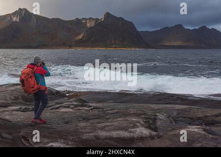 Impressioni autunnali dall'isola norvegese Senja sopra il Circolo polare Artico, Scandinavia e Norvegia pure, donna con zaino che scatta foto, Foto Stock