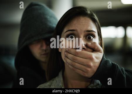 No, questo non può accadere. Una giovane donna terrorizzata tenuta prigioniera da un uomo con la mano sopra la bocca. Foto Stock