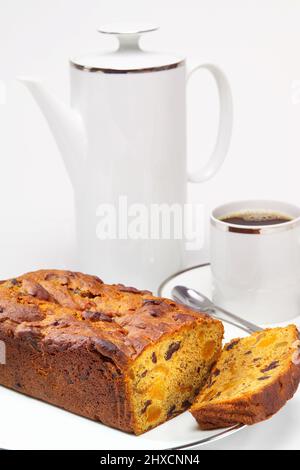 Caffettiera e tazza in stile retrò bianca contenente caffè nero con torta di frutta in primo piano. Foto Stock