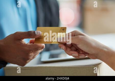 Paga il tuo acquisto a credito. Scatto ritagliato di un cliente utilizzando una carta di credito per pagare una consegna effettuata da un corriere. Foto Stock