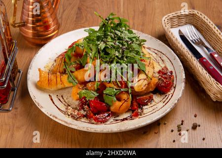 Insalata tradizionale italiana Angioletti con pomodori ciliegia, rucola, basilico, olio d'oliva e crema balsamica su tavola di legno. Foto Stock