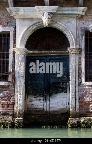 Antica porta ad arco direttamente sul canale di Venezia Foto Stock